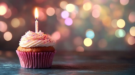 Festive birthday cupcake with lit candle and colorful frosting against warm bokeh lights background, celebration concept




