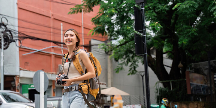 Urban travel. Happy woman exploring city streets with camera in hand.