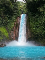 Stunning waterfall cascading into turquoise pool surrounded by lush tropical vegetation, showcasing the raw beauty of nature in a rainforest setting