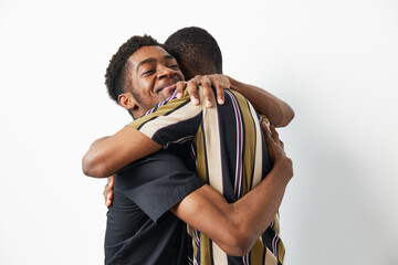 Two smiling black men sharing a warm embrace, showcasing friendship and connection. The colorful...