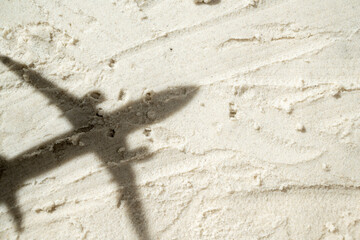 Shadow of an airplane flies over a beautiful sandy beach. Natural background. Summer concept. Top...