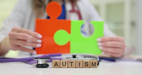 Wooden blocks form word Autism lying by big puzzle pieces. Pediatrician uses bright puzzles showing connection between brain and disorder for patient - Powered by Adobe