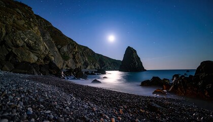 Tranquil moonlit shoreline with soft reflections on water and textured foreground rocks — great for landscapes, wallpaper, scenic view, nighttime designs and calm nature content