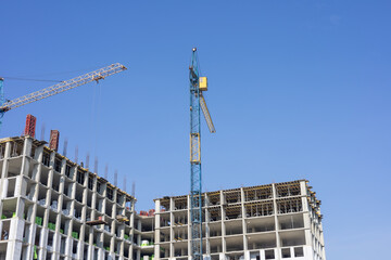 Busy construction site features cranes working on a high-rise building, with blue skies providing a...