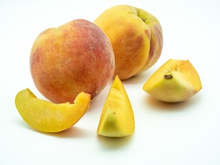 Fresh peaches and slices on a white background.