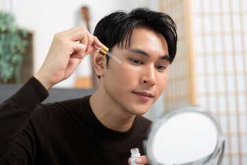 Skincare Routine. Young man applying serum for glowing skin.