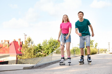 Happy couple roller skating together on street. Space for text