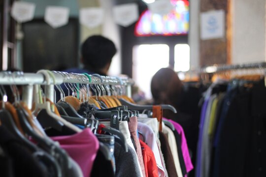 Roupas em cabides na feira de moda circular em economia sustent&aacute;vel com pessoas desfocadas ao fundo