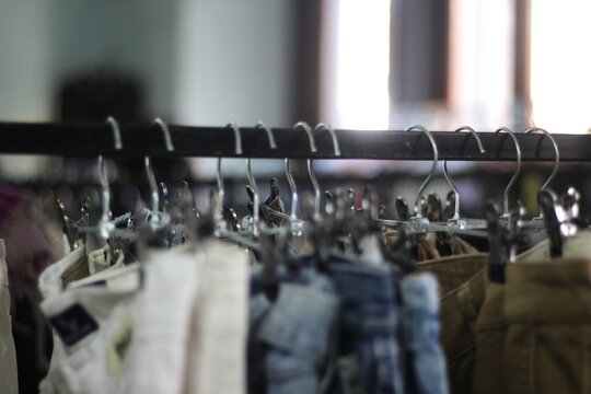 Roupas usadas em cabides na feira de moda circular com fundo desfocado.