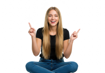 A happy young woman in a black tshirt and jeans sits crosslegged, pointing upwards with both index fingers isolated on transparent background