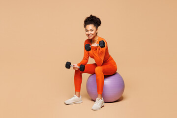 Full body young fitness trainer instructor sporty woman sportsman wear orange clothes spend time in...
