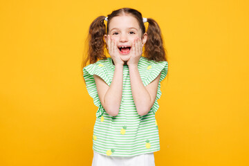 Little surprised happy cheery cute kid child girl 8-9 years old wears green t-shirt cover mouth...