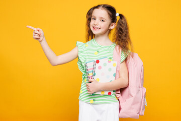 Little smiling kid child school girl 8-9 years old she wears green t-shirt backpack hold books...