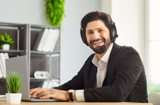 Businessman happy smiling, call service man wearing headset sitting at office desk, typing on laptop, happily, friendly professional, providing customer support in online communication, remote work