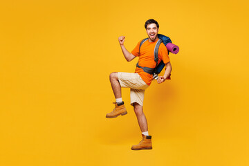 Side view young winner happy traveler man carrying backpack with stuff mat isolated on plain yellow...