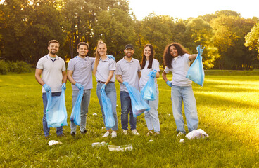 Portrait of a happy volunteer group tackling garbage cleanup in city park, removing trash and...