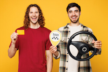 Young smiling two friends buddies men they wearing casual clothes together hold credit bank card taxi card sign steering wheel driving car isolated on plain yellow orange background Lifestyle concept