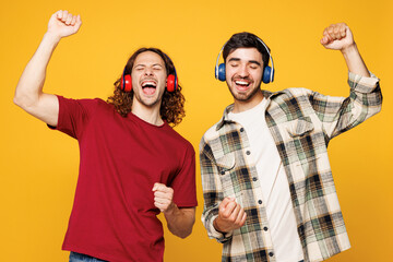 Young happy two friends buddies men they wear casual clothes together listen to music in headphones...