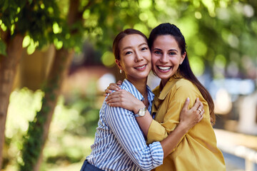 Fototapeta premium Two Happy Women Embracing Outside on a Sunny Day with Bright Smiles