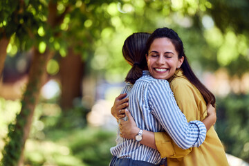 Two Women Hugging in a Green Park Environment on a Bright Day