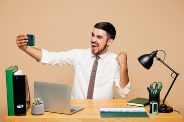 Young employee business man in white shirt tie sit work at office desk with pc laptop do mobile...