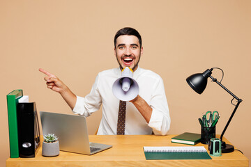 Young fun employee business man in shirt tie sit work at office desk with pc laptop scream in...