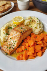 Savor an Elegant & Healthy Dinner: Perfectly Cooked Salmon Fillet Served with Creamy Mashed Potatoes, Glazed Carrots, and a Zesty Lemon Wedge, a Nutritious and Flavorful Main Course.
