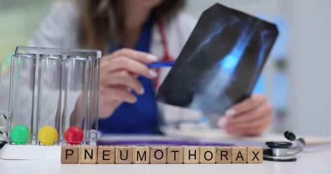 Word Pneumothorax on blocks and incentive spirometer on doctor desk. Woman pulmonologist examines lungs X-ray image in hospital slow motion