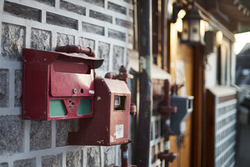 Vintage red mailboxes on traditional Korean brick wall in Bukchon Hanok Village at sunset