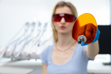 A Professional in Protective Gear Demonstrates a Unique Dental Instrument in a Modern Clinic...