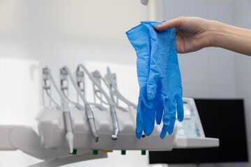 A Close-Up of a Person's Hand Holding Blue Surgical Gloves in a Dental Clinic Setting with Dental...
