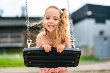 Happy 5 years old girl on a swing. Happy kid on playground