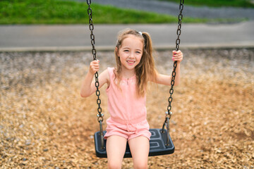 Happy 5 years old girl on a swing. Happy kid on playground
