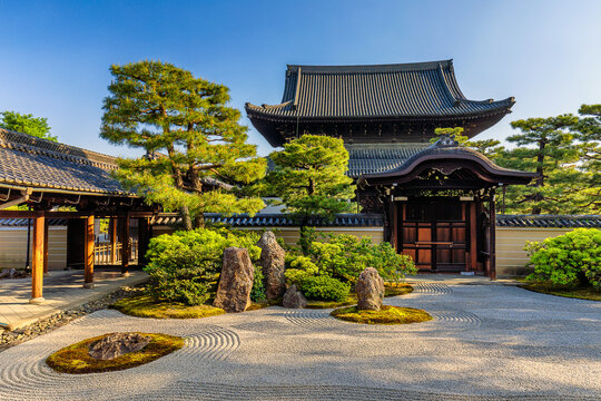 View of a serene Japanese Zen garden featuring meticulously raked gravel, sculpted trees, and traditional architecture under a clear sky, Kyoto, Kyoto, Japan.