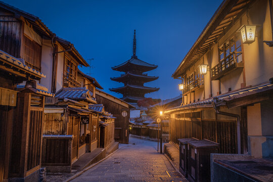 View of traditional wooden buildings line a narrow street leading to a towering pagoda under a twilight sky, Kyoto, Kyoto, Japan.