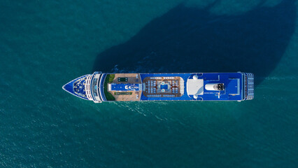 Aerial top view of a luxury cruise ship sailing through deep blue ocean water. Vibrant deck design...