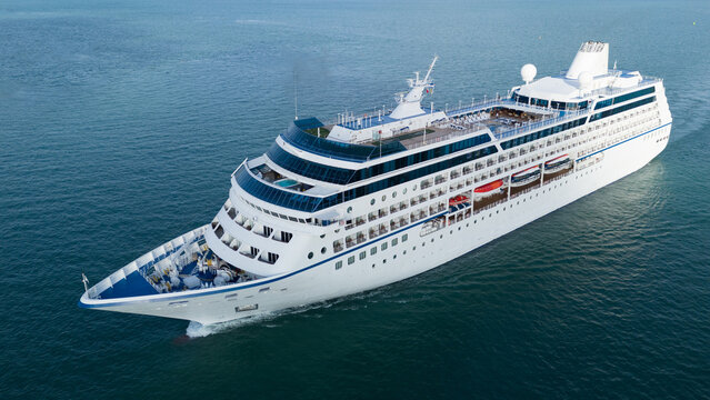 Aerial top view of a luxury cruise ship sailing through deep blue ocean water. Vibrant deck design with pools, sun loungers, and activity zones, ideal for travel, vacation, and maritime lifestyle