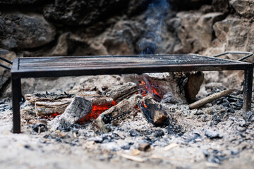 open fire with grill rack set on natural stones in a rustic outdoor setting