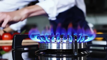 A bright blue flame burns on a modern gas stove, showcasing culinary preparation and cooking energy in the kitchen.