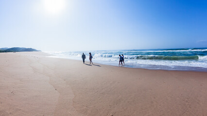 Beach Ocean Morning Bright Sunshine Four Girls walking In The Distance Silhouetted on the Coastline Landscape.
