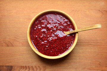 Delicious puree of ripe raspberries in a wooden bowl with a wooden spoon. Ripe raspberries. Flat lay, top view.