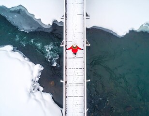 Aerial view of a person on a snowy bridge over a frozen river