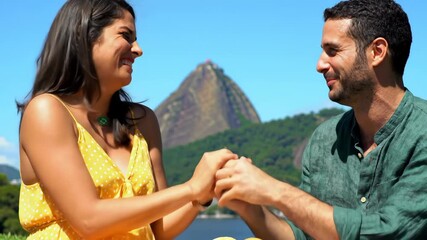 young romantic brazilian couple in green and yellow enjoying picnic. celebrating independence day with sugarloaf mountain in background. sense of national pride and togetherness.