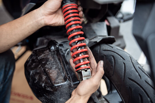 Motorcycle mechanic check and change rear Shock Absorbers motorcycle at motorcycle garage, Damaged Struts and fluid leaks among struts and shocks ,repair, maintenance and service concept