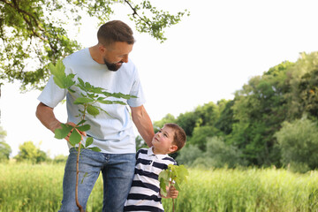 Father and his son planting tree outdoors, space for text