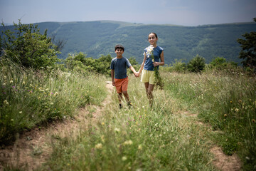 Fototapeta premium Brother and sister holding hands walking on country path