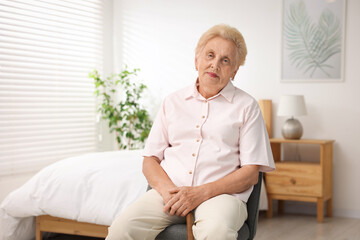 Senior woman with walking cane in armchair at home