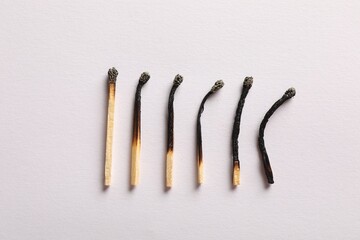 Burnt matches on light grey background, flat lay