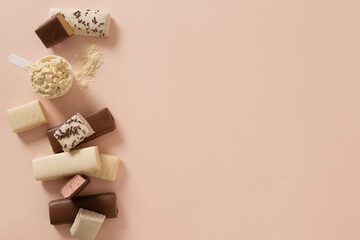 Protein bars with various coatings and sprinkles scoop of protein powder on pink background....