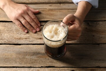 Man with glass mug of beer at wooden table, above view